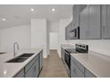 Bright kitchen features sleek grey cabinets, an island sink, and stainless steel appliances at 8560 Caribbean Pine Way, Lakeland, FL 33809