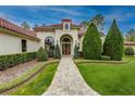 Elegant home exterior showcasing a paved walkway and manicured landscaping leading to the arched entryway at 16828 Vinci Way, Montverde, FL 34756