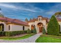 Stunning exterior view of a home with a tile roof, arched entry, and lush, well-maintained landscaping at 16828 Vinci Way, Montverde, FL 34756