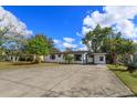 An exterior view showcasing a white house with modern design, complemented by a spacious driveway and green landscaping at 220 Lake Gene Dr, Longwood, FL 32779