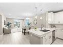Bright, open-concept kitchen with island, stainless appliances, modern lighting, and stylish dining area at 7573 Laureate Blvd # 1301, Orlando, FL 32827