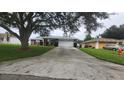 Front view of a house with a driveway and a tree at 7438 Floral W Cir, Lakeland, FL 33810