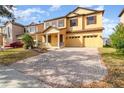 Two-story house with a yellow facade, brick driveway, and landscaping at 10064 Silver Laurel Way, Orlando, FL 32832