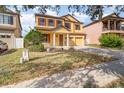 Two-story house with a yellow facade, brick driveway, and landscaping at 10064 Silver Laurel Way, Orlando, FL 32832