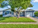 Newly painted blue home with a well-manicured lawn and driveway at 7685 Ceres Dr, Orlando, FL 32822