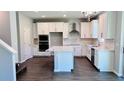 Modern kitchen features white cabinets, a kitchen island, stainless steel appliances, and hardwood floors at 1189 Basalt Ln, Sanford, FL 32771
