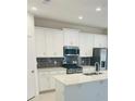 Modern kitchen featuring white cabinets, quartz countertops, and stainless steel appliances at 366 Switchgrass Loop, Minneola, FL 34715