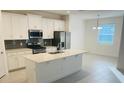 Open concept kitchen with island, white cabinets and gray backsplash at 366 Switchgrass Loop, Minneola, FL 34715