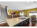 Open-concept kitchen featuring an island, wooden chairs, and seamless view into living area with a TV on the yellow wall at 205 Hamlet Rd, Davenport, FL 33837