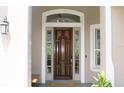 Elegant wooden front door with glass sidelights and transom, complemented by a welcoming porch light at 4901 Shoreline Cir, Sanford, FL 32771