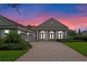 Gray house with columns, brick driveway, and sunset in the background at 6533 Cartmel Ln, Windermere, FL 34786