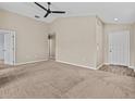 Spacious living room featuring neutral walls, carpet flooring, and a modern ceiling fan for added comfort at 2977 Kokomo Loop, Haines City, FL 33844
