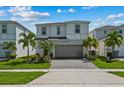 Inviting two-story home with a well-maintained lawn, palm trees, and a brick-paved driveway at 1697 Kona Ln, Davenport, FL 33897