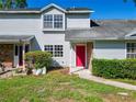 Traditional townhome with a well-manicured lawn, classic siding, a bright red front door, and mature trees at 1624 Rivers Edge Dr, Orlando, FL 32825