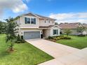 Beautiful two-story home with an attached gray garage door, accented by blue shutters and lush landscaping at 8060 Cherrystone St, Leesburg, FL 34748
