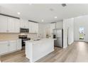 Modern kitchen with white cabinets, stainless steel appliances, a center island and wood-look floors at 1386 Current Pl, Haines City, FL 33844