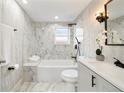 Bright bathroom features a shower over tub, white marble tile, vanity, and decorative black fixtures at 1321 Cloverlawn Ave, Orlando, FL 32806