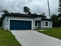 Newly constructed home with gray exterior, dark garage door, and grassy lawn at 3325 Sw 165Th Loop, Ocala, FL 34473