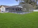 Backyard featuring a screened-in pool enclosure, lush green grass, and privacy fencing at 4814 Lake Shore Dr, St Cloud, FL 34772