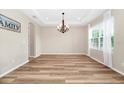 Bright dining room featuring hardwood floors, a modern chandelier, and a large window at 15558 Sandfield Loop, Winter Garden, FL 34787