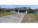 Single-story home with gray roof, gray two-car garage, freshly landscaped flowerbeds, and long driveway at 260 S Fairbairn Dr, Deltona, FL 32725