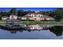 Elegant waterfront home reflecting in the lake, with a covered dock and beautifully landscaped grounds at 1965 Lake Markham Preserve Trl, Sanford, FL 32771
