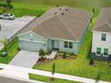 Aerial view of a one-story home with a brick driveway, manicured lawn, and nearby lake at 2585 Cavanaugh Dr, Orlando, FL 32817