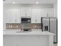 Modern kitchen featuring white cabinets, stainless steel appliances, and a stylish backsplash at 2585 Cavanaugh Dr, Orlando, FL 32817
