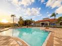 Resort-style community pool with ample seating, palm trees, and beautiful clubhouse on sunny day at 886 Grazie Loop, Davenport, FL 33837