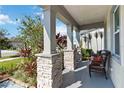 Front porch with stone pillars, wicker chair, and landscaping at 720 Split Hoof Dr, Saint Cloud, FL 34771