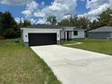 Charming single-story home with a black garage door, white stucco and well-manicured lawn at 442 Marion Oaks Crse, Ocala, FL 34473