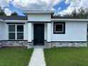 A close-up of the home's modern black front door, complemented by light stone accents at 442 Marion Oaks Crse, Ocala, FL 34473