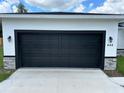 A black garage door on a stucco home with stone accents, and address number visible at 442 Marion Oaks Crse, Ocala, FL 34473
