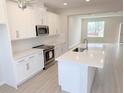 Modern kitchen features white cabinets, stainless steel appliances, and an island with a sink, open to the living area at 791 Pilea St, Apopka, FL 32703