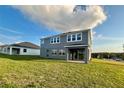 View of the back of this gray two-story home with a spacious green yard, blue skies and clouds at 3295 Roseville Dr, Apopka, FL 32712