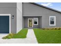 Close-up of the home's entrance featuring a modern wood door, neutral trim, and green landscaping at 4683 Sw 136Th St, Ocala, FL 34473