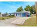 Single story home with a light blue exterior, red support beams, and a long concrete driveway at 926 Everett St, Lake Alfred, FL 33850