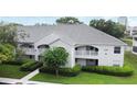 Exterior view of the property featuring white facade, grey roof, well-manicured lawn and mature trees at 570 Cranes Way # 248, Altamonte Springs, FL 32701