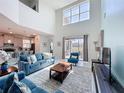 Bright living room with high ceilings, a large window, and sliding glass doors to the outside at 8938 Cabot Cliffs Dr, Davenport, FL 33896