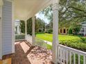Covered porch with white railings and brick flooring, offering a view of the landscaped community lawn at 2072 Hartz Aly, Orlando, FL 32814