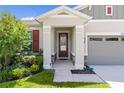 View of the home's front porch and door with landscaped flowerbeds at 10204 Spring Lake Dr, Clermont, FL 34711