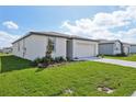 Exterior view of a single-Gathering home showcasing the lawn, white exterior, and a two car garage at 1344 Oak Valley Dr, Auburndale, FL 33823