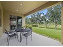 Covered patio with table and chairs, overlooking a large backyard at 12925 Holdenbury Ln, Windermere, FL 34786