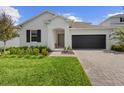 Inviting single-story home featuring a dark garage door, green lawn, and pretty landscaping at 4418 Lions Gate Ave, Clermont, FL 34711