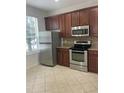 Kitchen with stainless steel appliances, brown cabinets, and tiled floor at 14460 Clarkson Dr, Orlando, FL 32828