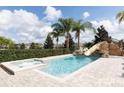 A private pool includes a spa and rock slide surrounded by palm trees for the ultimate vacation experience at 7554 Marker Ave, Kissimmee, FL 34747