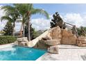 A stunning private pool features a rock slide and lush landscaping, perfect for relaxing and entertaining at 7554 Marker Ave, Kissimmee, FL 34747