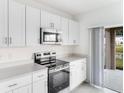 Modern kitchen featuring stainless steel appliances, white cabinets, and a sliding door to the backyard at 345 River Front Way, Edgewater, FL 32141