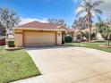 Tan house with a two-car garage and nicely landscaped lawn at 10324 Pleasant View Dr, Leesburg, FL 34788