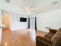 Inviting living room with wood floors, a modern ceiling fan, and a sliding glass door for natural light at 305 Erie Ct, Kissimmee, FL 34759